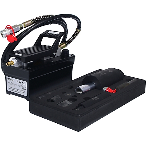 Schwarze hydraulische Fußpumpe mit Zubehör in einem Koffer. Schläuche, Manometer und Stecker sind erkennbar.